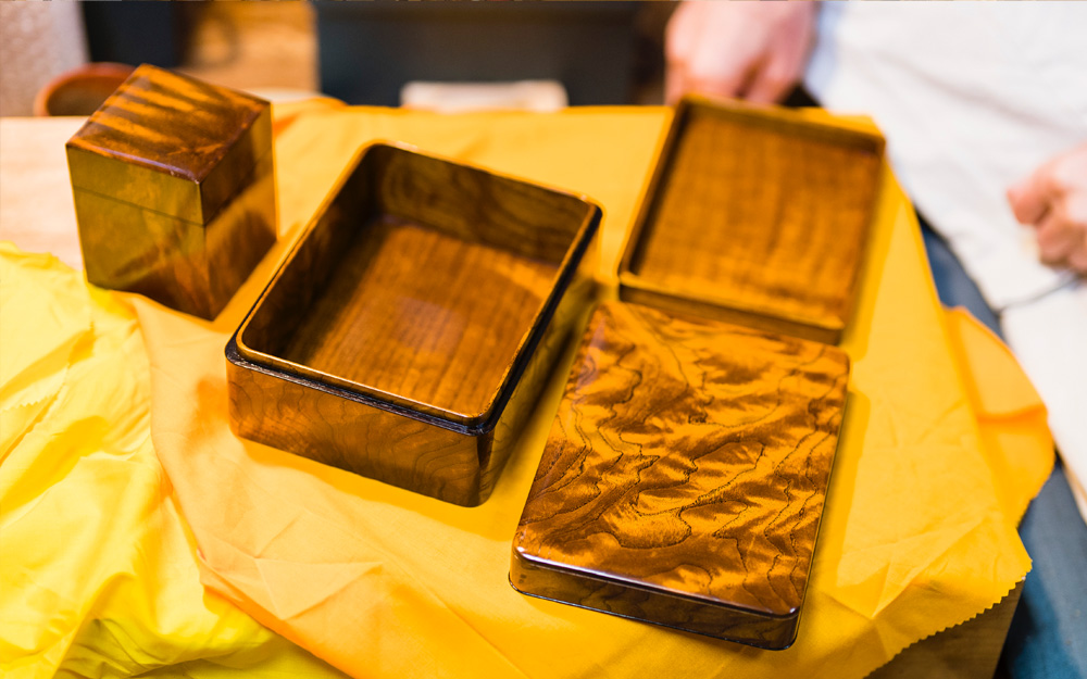 島桑拭漆印箱と島桑小箱（左奥）。余計な装飾を排して美しい杢目を生かすのが
江戸指物の特徴